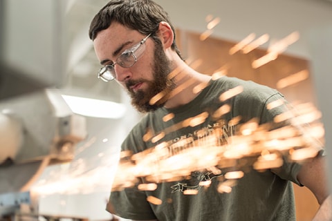 Student in trades lab with sparks flying.