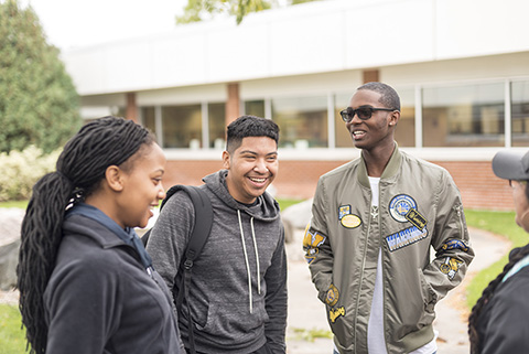 Group of students talking and laughing outside.